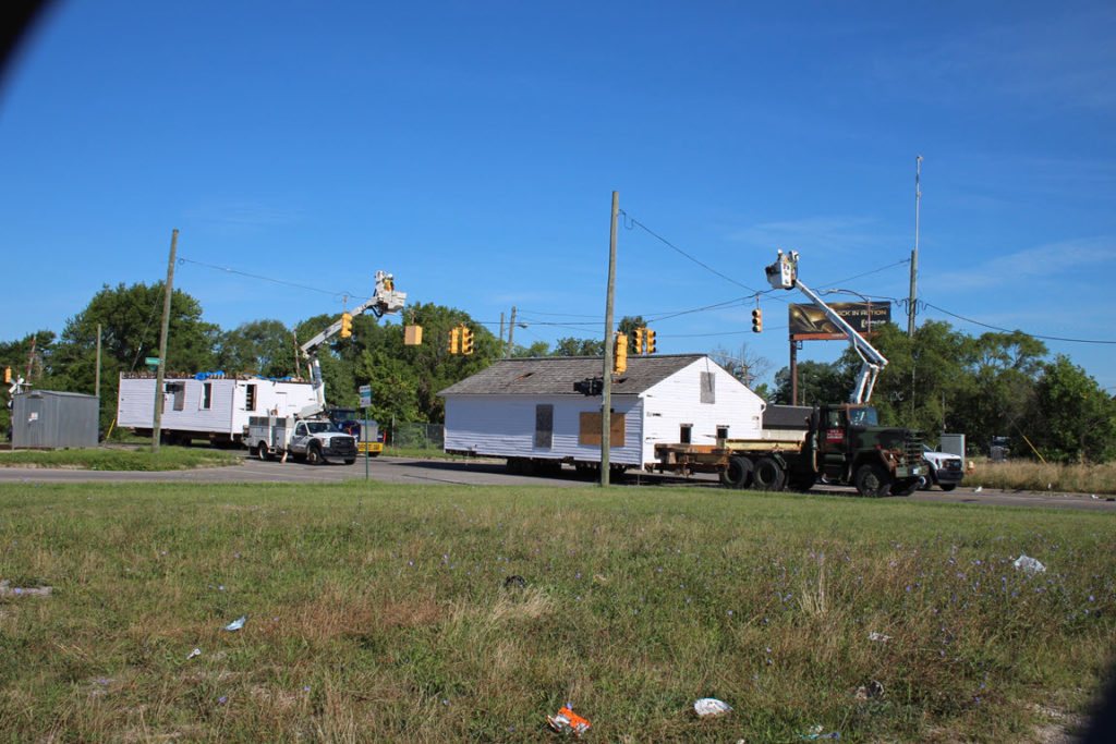 Two sets of linemen move two sets of traffic signals as the house passes under them.